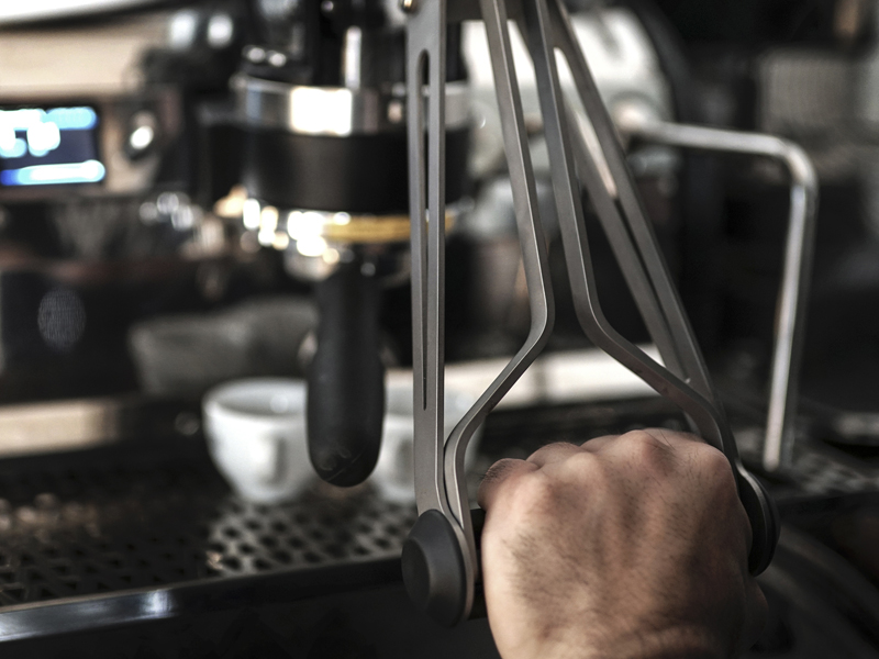 Image depicts a La Marzocco machine with a hand in the front of the picture.